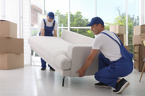 Moving-service-employees-carrying-sofa-in-room